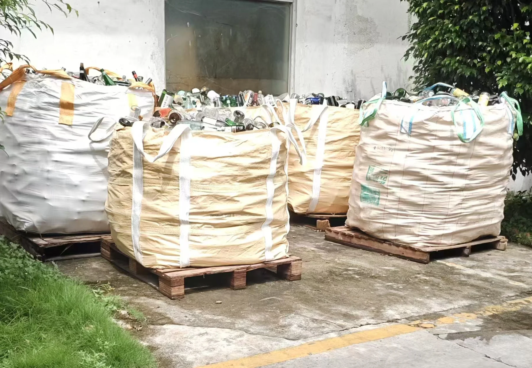Large bags of recovered glass stored on pallets at the factory