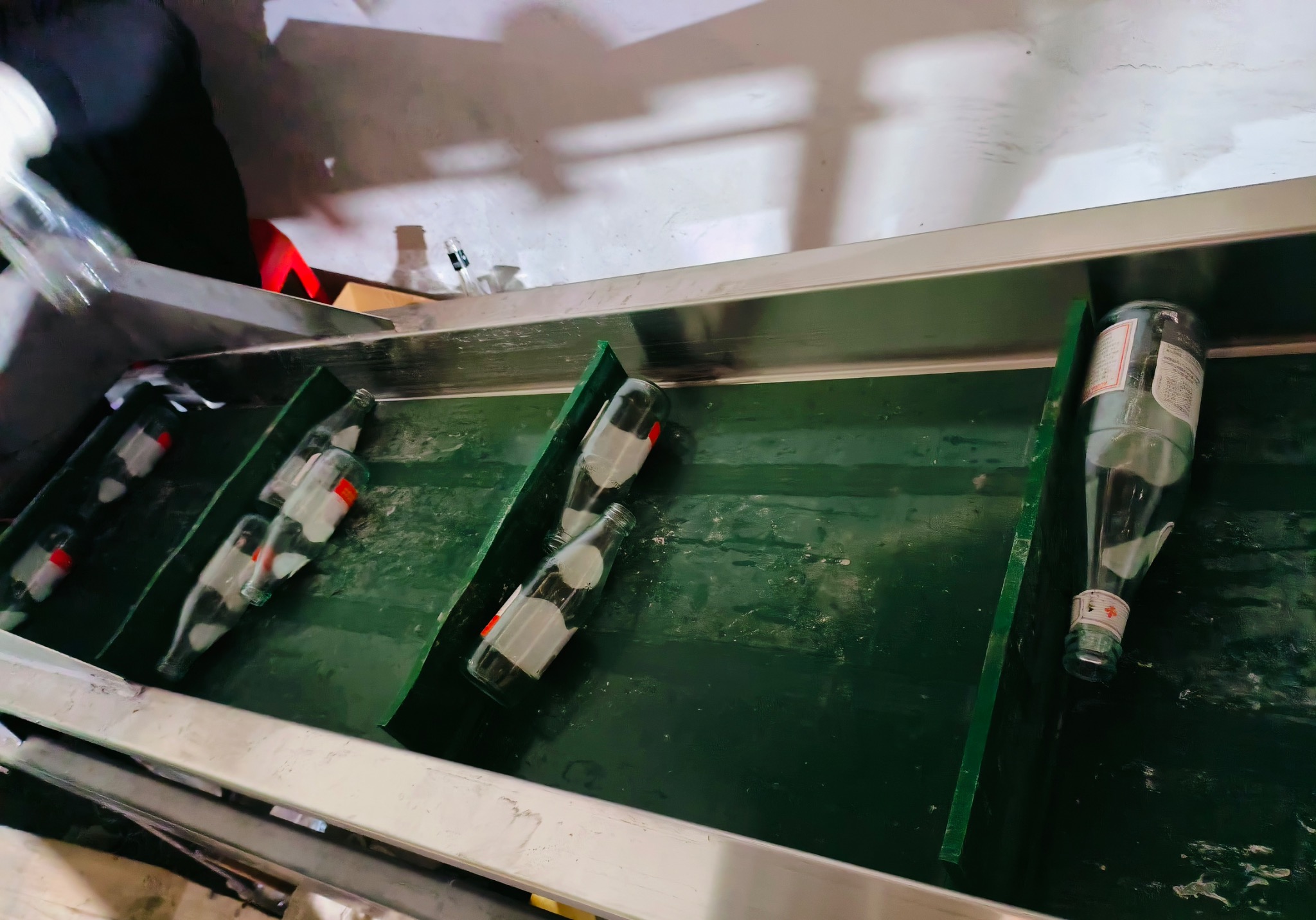 Recovered glass bottles on a green factory conveyor