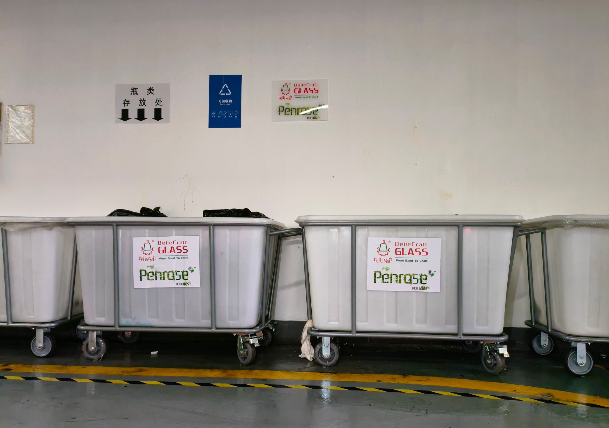 Labelled collection bins in wheeled frames lined up in a marked storage area