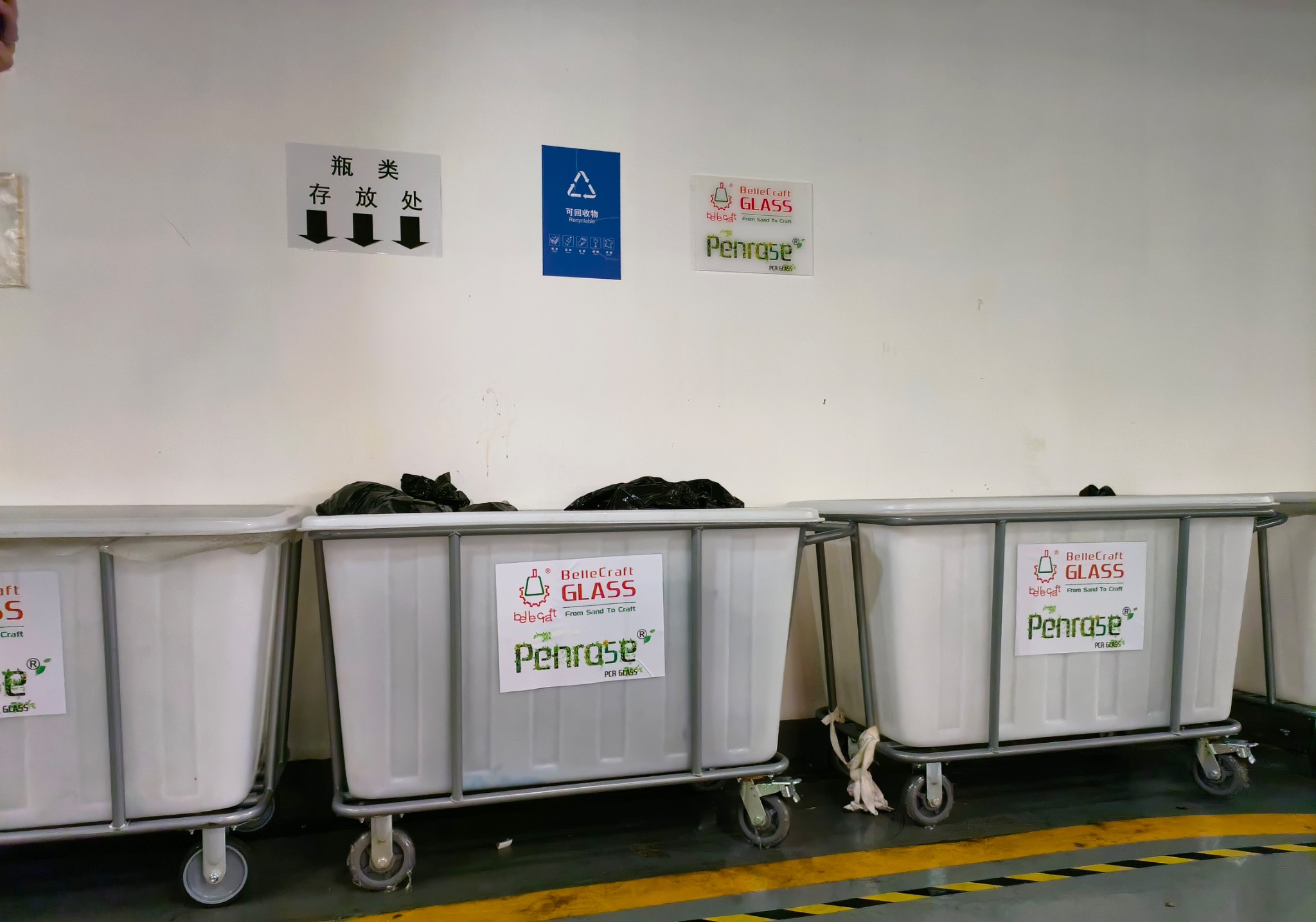 Large wheeled collection bins with BelleCraft and Penro5e labels beneath bottle-storage signs